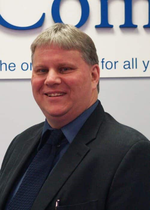 A man in a suit standing in front of a sign.