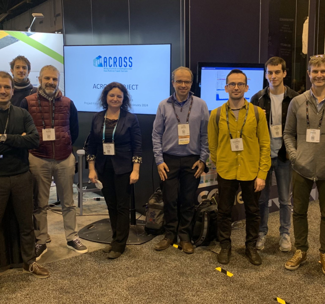 Group of eight people attending SuperComputing 2021, posing at a conference booth with a banner reading "ACROSS PROJECT," all smiling and wearing name badges.