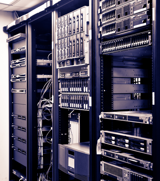 A black and white photo of open server racks filled with various network equipment and cables in a federal data center.