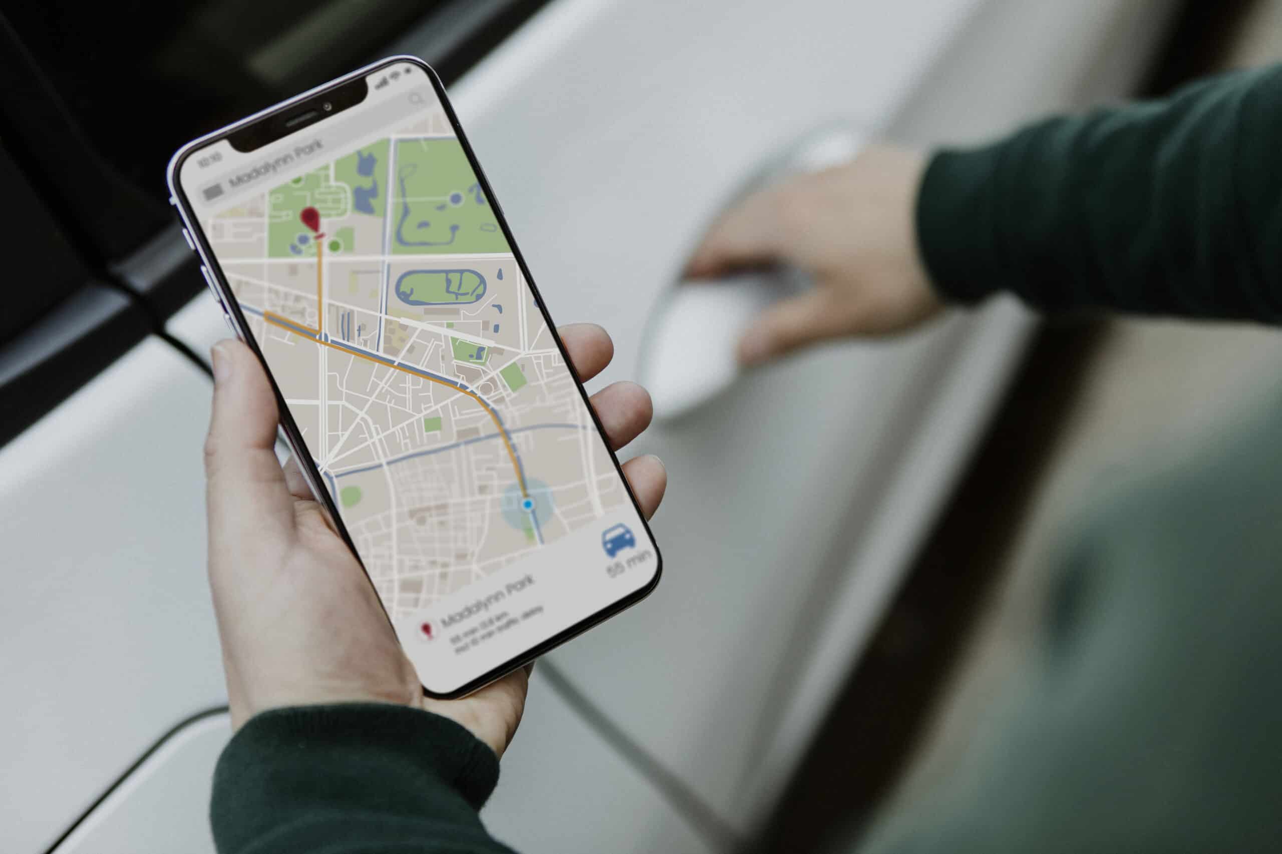 Person holding a smartphone displaying a map navigation app with directions to Madison Park, while opening a car door—perfect for demonstrating smartphone forensic search in real-world scenarios.