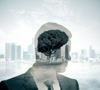 Double exposure of a man in a suit with a tree and city skyline superimposed, symbolizing ESG values as the tree appears within his silhouette, blending urban progress with environmental consciousness.