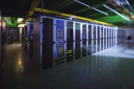 A row of server racks with illuminated equipment and cables in a modern data center, optimized for virtualization and AI training.