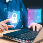 A person using a laptop, interacting with a digital padlock icon, represents cybersecurity and data protection, showcasing advanced technology at an AFITC event.