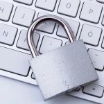 A metal padlock rests on top of a white computer keyboard.