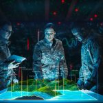 Three military personnel from an IT services company analyze a holographic terrain map in a dimly lit room with digital data displays.